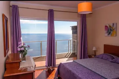 a bedroom with a large window with purple curtains at Benoni House by Stay Madeira Island in Ponta do Sol