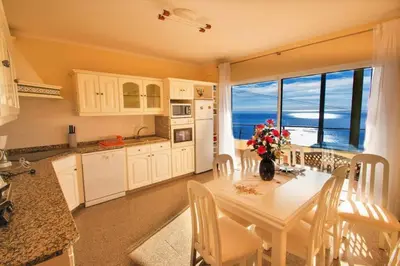 a kitchen with a table with a vase of flowers on it at Benoni House by Stay Madeira Island in Ponta do Sol