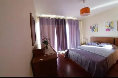 a bedroom with a bed and a window with purple curtains at Benoni House by Stay Madeira Island in Ponta do Sol