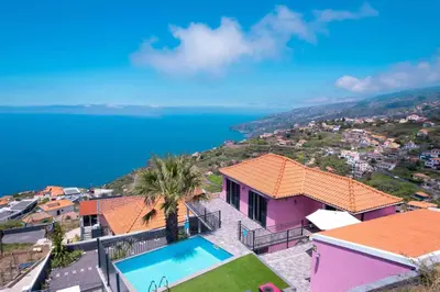 a house on a hill with the ocean in the background at Villa Rosa with private pool by Holiday Rental Madeira in Ribeira Brava