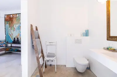 a bathroom with a toilet and a chair at Moinho Calmo in Vila do Bispo