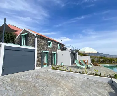 a house with a garage door and a patio at The Hideaway Madeira in Prazeres