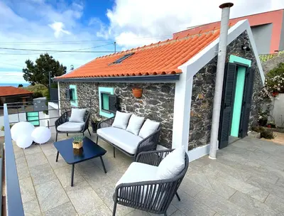 a patio with chairs and a table and a building at The Hideaway Madeira in Prazeres