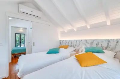 two beds in a room with white walls at The Hideaway Madeira in Prazeres