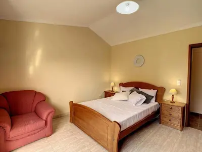 a bedroom with a bed and a red chair at Vila Feliz in Paul do Mar