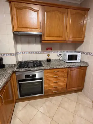 a kitchen with wooden cabinets and a stove and a microwave at Cool Apartment in Porto Santo