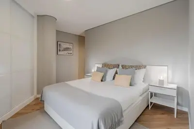 a white bedroom with a large white bed and a nightstand at The Mountain Apartment by An Island Apart in Funchal