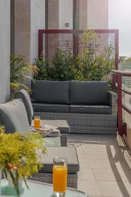 a couch on a balcony with two glasses of orange juice at The Mountain Apartment by An Island Apart in Funchal