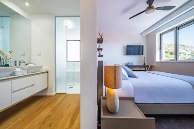 a bedroom with a bed and a bathroom with a sink at Maha by KAAMAH - 2 Bedroom OceanView Designer Apartment in Funchal