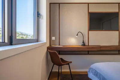 a bedroom with a desk and a bed and a chair at Maha by KAAMAH - 2 Bedroom OceanView Designer Apartment in Funchal