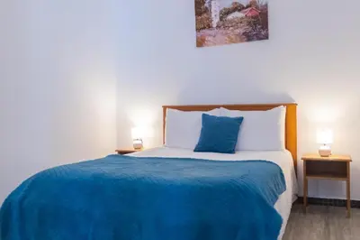 a bedroom with a bed with a blue blanket and two lamps at Casa Luz - Arco da Calheta in Arco da Calheta