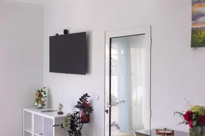 a white room with a door with a television on the wall at Casa Luz - Arco da Calheta in Arco da Calheta