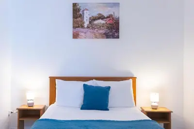 a bed with a blue pillow and two night stands at Casa Luz - Arco da Calheta in Arco da Calheta