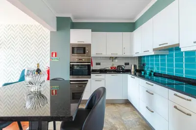 a kitchen with white cabinets and blue tiles at Calandiva in Caniço