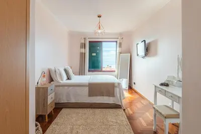 a white bedroom with a bed and a window at Calandiva in Caniço