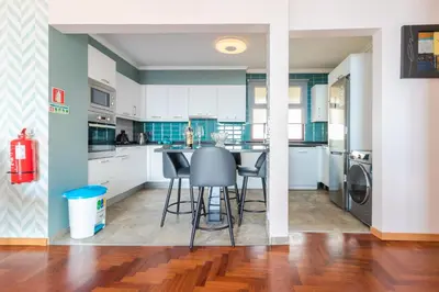 a kitchen with white cabinets and a table and chairs at Calandiva in Caniço
