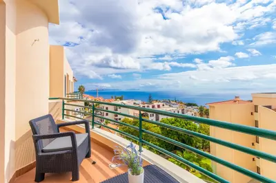 a balcony with a chair and a view of the ocean at Calandiva in Caniço