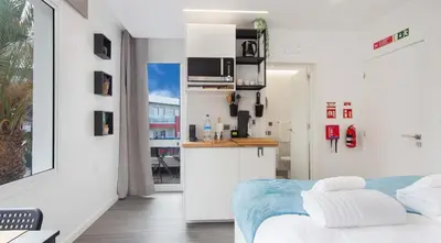 a white room with a bed and a kitchen at The Jolie - Apartments by the Ocean in Porto Moniz