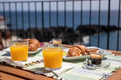 a table with orange juice and croissants and bread at Casa do Ilhéu - House of Ilhéu - Câmara de Lobos in Câmara de Lobos