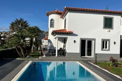 a white house with a swimming pool in front of it at Funchal Apt- Sleeps 2 - Pool & Parking - Madeira in Funchal