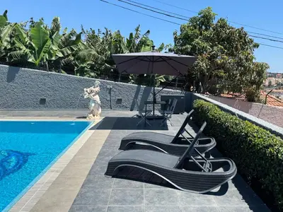 a pair of chairs and an umbrella next to a swimming pool at Funchal Apt- Sleeps 2 - Pool & Parking - Madeira in Funchal