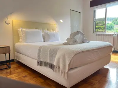a bedroom with a large white bed with a teddy bear on it at Villa do Monte in Porto Moniz