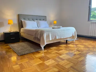 a bedroom with a bed with a wooden floor and two lamps at Villa do Monte in Porto Moniz