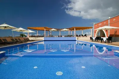 a swimming pool with chairs and umbrellas on a building at Villa Bougainvillea Palheiro Village by Holiday Rental Madeira in Funchal