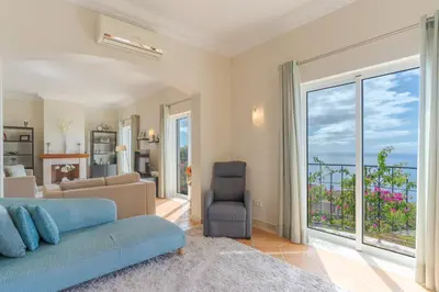 a living room with a blue couch and a window at Villa Bougainvillea Palheiro Village by Holiday Rental Madeira in Funchal