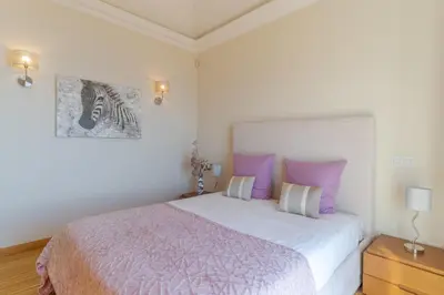 a bedroom with a large bed with purple pillows at Villa Bougainvillea Palheiro Village by Holiday Rental Madeira in Funchal