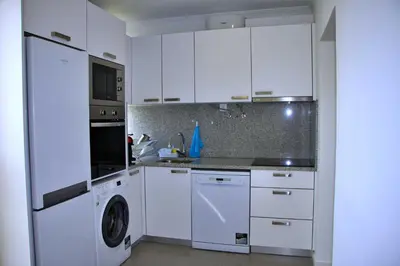a kitchen with white cabinets and a washer and dryer at Apartamento DAVI in Funchal