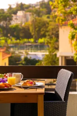 a table with a plate of food and a cup of orange juice at Camoes Apartment by Atlantic Holiday in Funchal