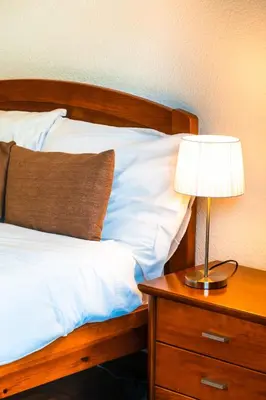 a bed with a table with a lamp on it at Camoes Apartment by Atlantic Holiday in Funchal
