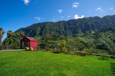 a red shed in a field with mountains in the background at Quinta Vale Vitis in São Vicente