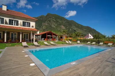 a swimming pool in front of a house with a mountain at Quinta Vale Vitis in São Vicente
