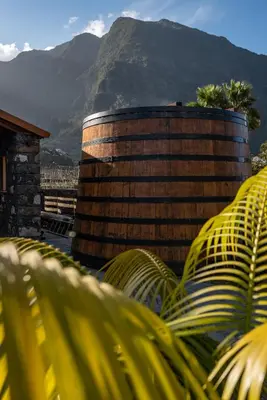 a large wooden barrel with a mountain in the background at Quinta Vale Vitis in São Vicente