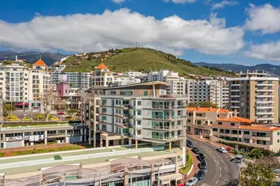 a city with buildings and a hill in the background at Rodamar II by An Island Apart in Funchal