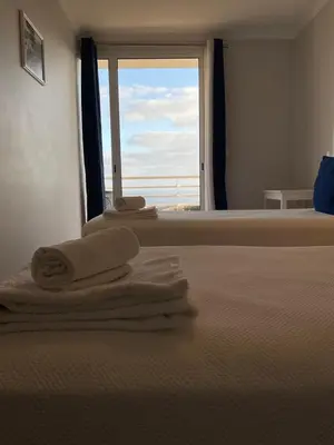 a bedroom with towels on a bed with a window at Sol & Mar Rancho in Câmara de Lobos