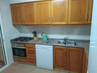 a kitchen with wooden cabinets and a sink at Sol & Mar Rancho in Câmara de Lobos