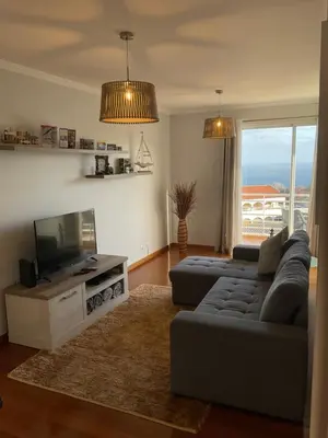 a living room with a couch and a flat screen tv at Sol & Mar Rancho in Câmara de Lobos
