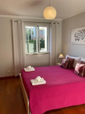 a bedroom with a large pink bed with towels on it at Sol & Mar Rancho in Câmara de Lobos