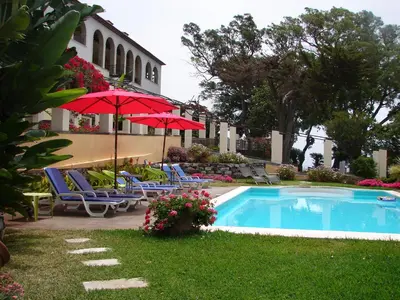 a pool with chairs and umbrellas next to a building at Private Pool Apt. with Great View in Funchal