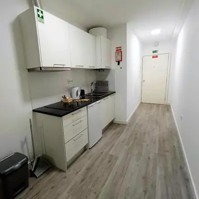 a kitchen with white cabinets and a wooden floor at Tanoeiros Studios in Funchal