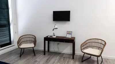 two chairs and a desk with a television on a wall at Tanoeiros Studios in Funchal