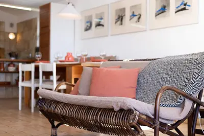 a living room with a rattan couch and a kitchen at Casa do Barco in Luz