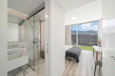 a bathroom with a bed and a sink and a mirror at OurMadeira - Ocean Panorama in Estreito da Calheta