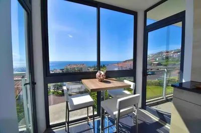a table and chairs in a room with windows at Rubeus in Caniço