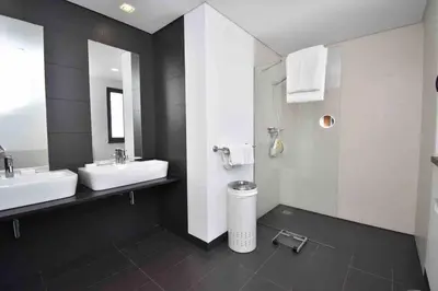 a large bathroom with two sinks and a shower at Rubeus in Caniço