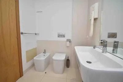 a white bathroom with a toilet and a sink at Rubeus in Caniço