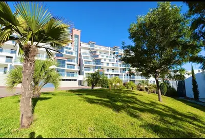 a large apartment building with palm trees in a park at Rubeus in Caniço